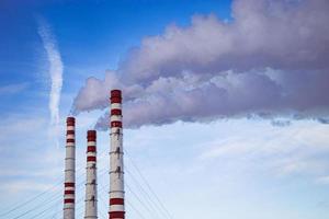 Air pollution. Smoking chimneys against blue sky. photo