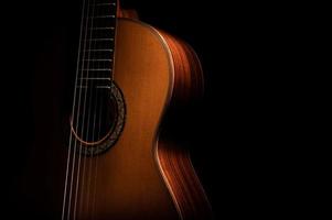 Classical guitar close up, dramatically lit on a black background with copy space. photo