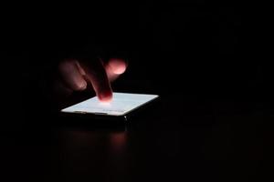 Close-up. female fingers is playing  smartphone on table. Blurred dark background. At night photo