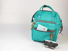 green backpack with passport cover and camera on white background with copy space.. Travel accessories concept. photo