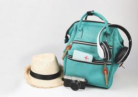 green backpack with passport cover, headphones, camera and straw hat  on white background with copy space.. Travel accessories concept. photo