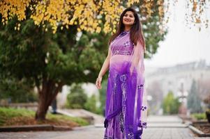 Indian hindu girl at traditional violet saree posed at autumn street. photo