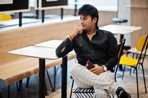Stylish indian man sitting at fast food cafe and waiting his order. photo