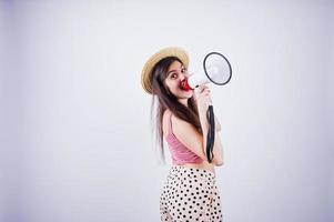 Portrait of a gorgeous young girl in swimming suit and hat talks into megaphone in studio. photo