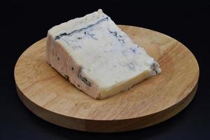 rebanada de queso gorgonzola italiano tradicional aislado sobre fondo negro foto