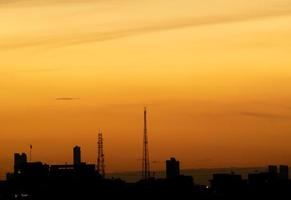 Gives a warm feeling,sunset behind the city building,silhouette city tall buildings,building silhouette again beautiful sky background and freedom concept. photo