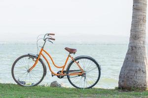 bicicleta naranja con el telón de fondo de las montañas y el mar con un cálido sol. foto