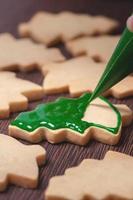 Close up of drawing Christmas tree sugar cookie on wooden table background with icing. photo