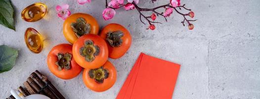 Top view of fresh sweet persimmons with leaves on gray table background for Chinese lunar new year photo