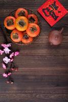 Top view of fresh sweet persimmons with leaves on wooden table background for Chinese lunar new year photo