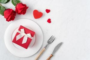 plato con vajilla, cinta, regalo y rosas para el concepto de comida especial del día de san valentín.