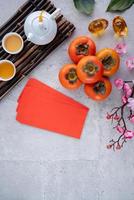 Top view of fresh sweet persimmons with leaves on gray table background for Chinese lunar new year photo