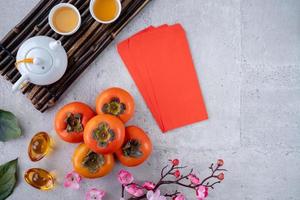 Top view of fresh sweet persimmons with leaves on gray table background for Chinese lunar new year photo