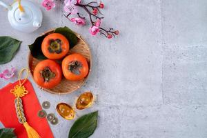 Top view of fresh sweet persimmons with leaves on gray table background for Chinese lunar new year photo