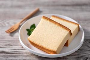 Castella kasutera - Delicious Japanese sliced sponge cake food on white plate over rustic wooden table, close up, healthy eating, copy space design. photo