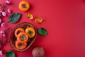 Top view of fresh sweet persimmons with leaves on red table background for Chinese lunar new year photo