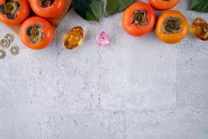 Top view of fresh sweet persimmons with leaves on gray table background for Chinese lunar new year photo