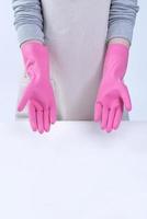 una joven ama de llaves en delantal lleva guantes rosas para limpiar la mesa, concepto de prevención de infecciones por virus, servicio de limpieza, cierre. foto