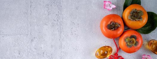 Top view of fresh sweet persimmons with leaves on gray table background for Chinese lunar new year photo