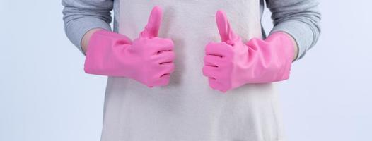 una joven ama de llaves en delantal lleva guantes rosas para limpiar la mesa, concepto de prevención de infecciones por virus, servicio de limpieza, cierre. foto