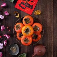 Top view of fresh sweet persimmons with leaves on wooden table background for Chinese lunar new year photo