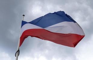 Schleswig Holstein flag at a flagpole moving slowly in the wind against the sky photo