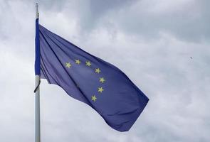 European Union flag at a flagpole moving slowly in the wind against the sky photo