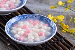 Close up of red and white tangyuan in blue bowl on wooden background for Winter solstice. photo