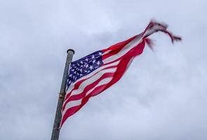 USA flag at a flagpole moving slowly in the wind against the sky photo