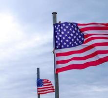 USA flag at a flagpole moving slowly in the wind against the sky photo