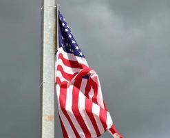 bandera de estados unidos en un asta de bandera moviéndose lentamente en el viento contra el cielo foto