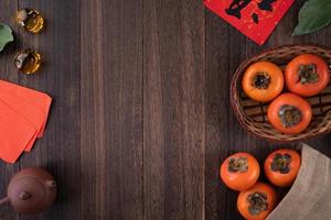 Top view of fresh sweet persimmons with leaves on wooden table background for Chinese lunar new year photo