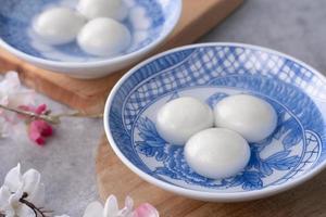 primer plano de tangyuan en un recipiente sobre una mesa gris, comida para el solsticio de invierno. foto