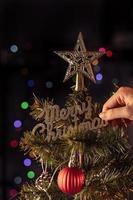 Christmas background concept- beautiful decor bauble hanging on the Christmas tree with sparkling light spot, blurry dark black background, copy space, close up. photo