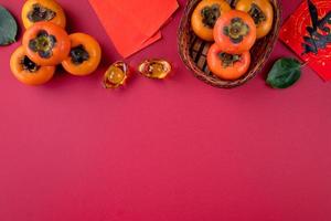 vista superior de caquis dulces frescos con hojas en el fondo de la mesa roja para el año nuevo lunar chino foto