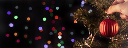 Christmas background concept- beautiful decor bauble hanging on the Christmas tree with sparkling light spot, blurry dark black background, copy space, close up. photo