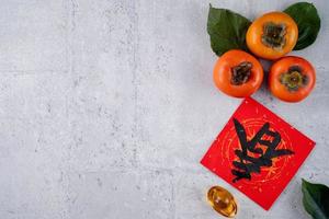 Top view of fresh sweet persimmons with leaves on gray table background for Chinese lunar new year photo