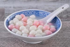 Close up of red and white tangyuan in blue bowl on wooden background for Winter solstice. photo