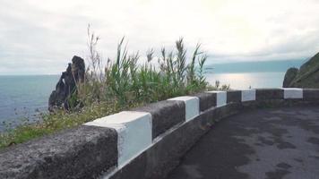 Paved seaside road with a view of large rock formations and ocean horizon view video