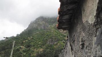 Close up of old stone building side and roof with foggy mountain background video