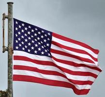 USA flag at a flagpole moving slowly in the wind against the sky photo