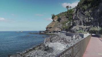 passerelle avec garde-corps se déplace le long de la mer avec des montagnes rocheuses video