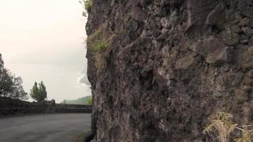 Turning on a curvy road with rock bluff and ocean view video