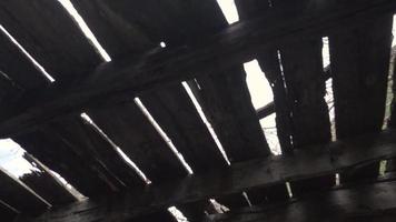 Light filters through cracks in wooden floor boards seen from below