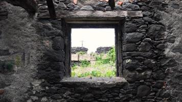 vista attraverso la finestra della casa di pietra abbandonata nel prato erboso video