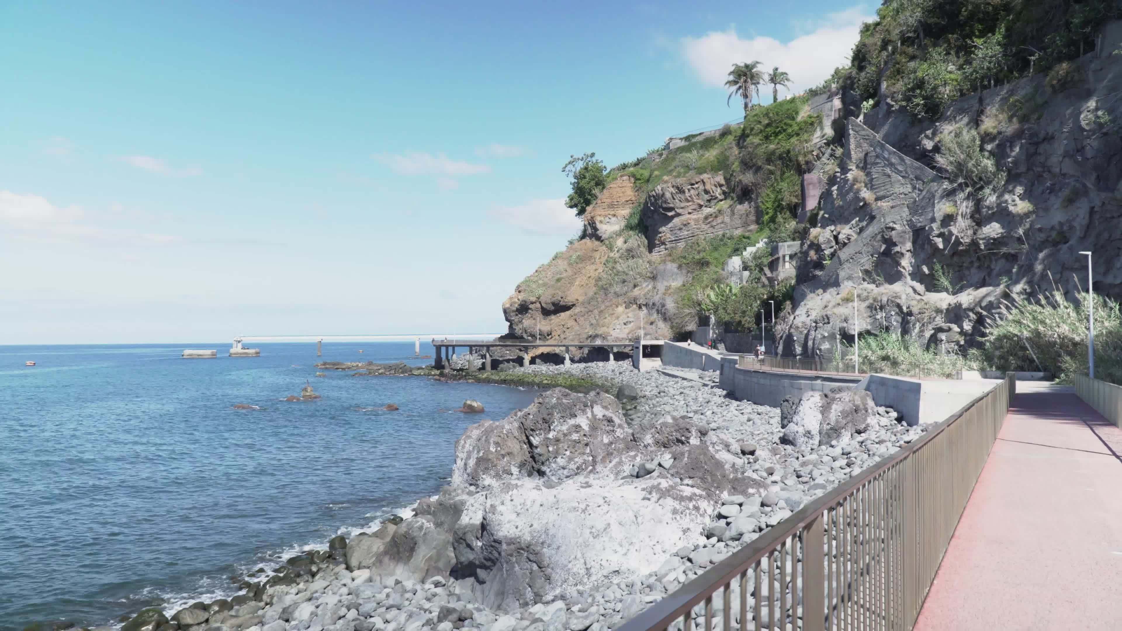 Seaside walkway with railing with rock mountains in the distance