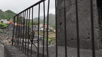 Blick durch Eisengeländer der alten Steinstruktur zeigt rustikales Dorf video