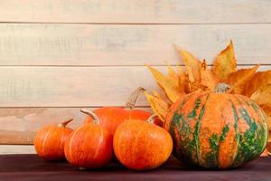 Autumn harvest. Ripe pumpkins and fallen leaves on wooden background. Thanksgiving and halloween concept. photo