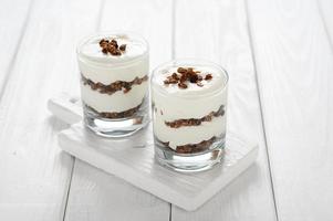 Dessert with mascarpone cheese and granola on a white wooden background. photo
