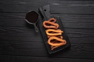 churros caseros con chocolate sobre un fondo rústico de madera oscura. foto